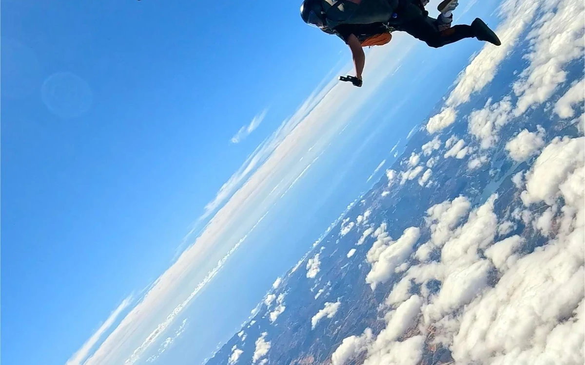 A small plane and a single skydiver high against the clouds over the Algarve