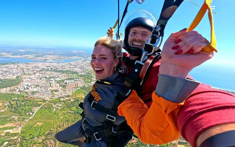 A tandem pair under the open canopy, smiling at the camera above the town and the estuary