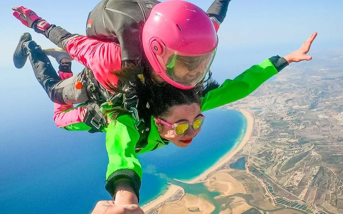 A tandem pair in freefall above the coast, the sea and a sandbar below